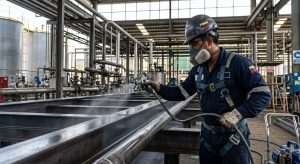 Técnico venezolano aplicando recubrimiento con nanotecnología en instalación industrial con equipo airless, luz natural destacando la aplicación precisa y uniforme sobre superficie metálica.